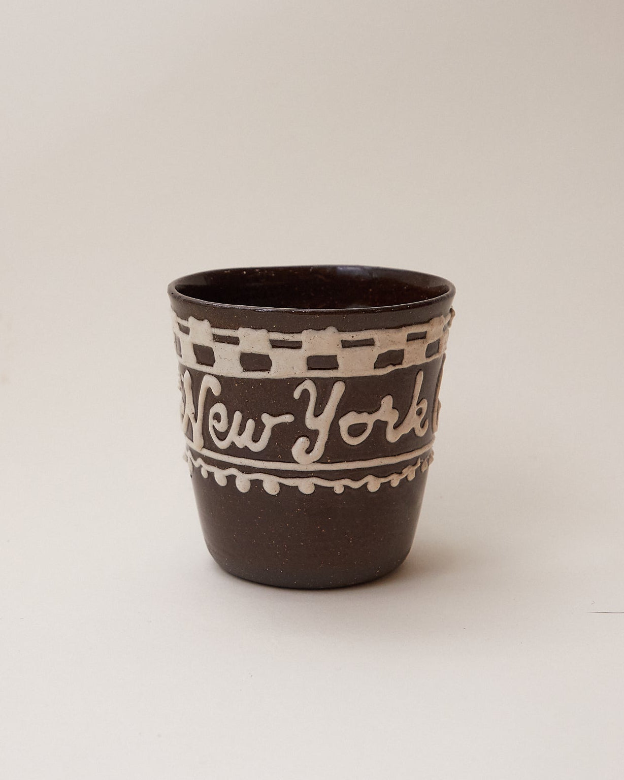 Handmade Brown and beige ceramic cup with 'New York' text and checker pattern